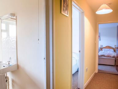 A hallway with doorways leading to bedrooms and a bathroom with a sink at Shepherds Retreat in Gortin