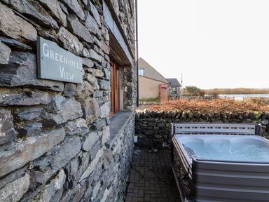 A stone building with a sign reading greenhills view and a hot tub on a paved area at Green Hills Farm in Ulverston