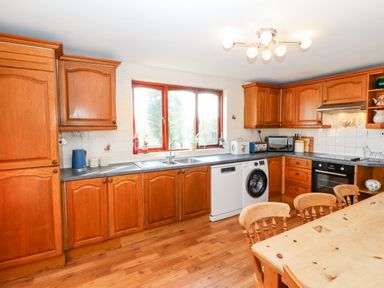 A kitchen with wooden cabinets and a dining table with chairs at Green Hills Farm in Ulverston