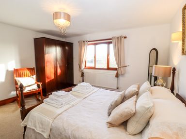 A bedroom with a bed with pillows and folded towels a wooden chair a wardrobe and a window at Green Hills Farm in Ulverston