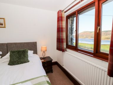 A bedroom with a bed and bedside table and a window showing a river view at Green Hills Farm in Ulverston