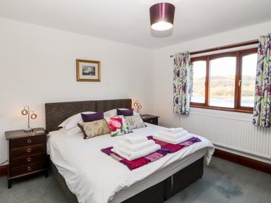 A bedroom with a double bed and pillows with folded towels on the bed at Green Hills Farm in Ulverston