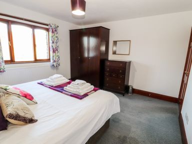 A bedroom with a bed, folded towels on the bed, a wardrobe, and a chest of drawers at Green Hills Farm in Ulverston