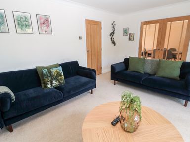 A living room with two dark sofas and a round wooden coffee table with a plant at The Croft in Longhoughton near Alnwick