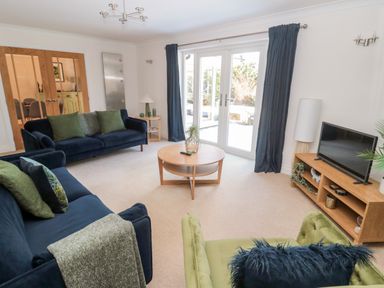 A living room with two blue sofas and one green armchair a wooden coffee table and TV unit with a TV at The Croft in Longhoughton near Alnwick