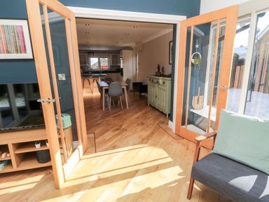 A room with wooden floor and glass doors leading to a dining area with table and chairs at The Croft in Longhoughton near Alnwick