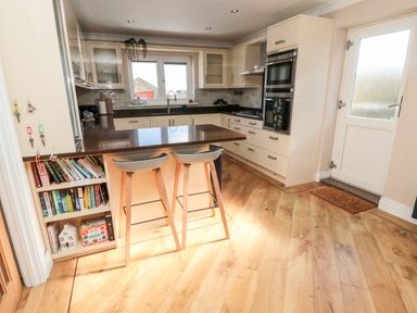 A kitchen with countertop stools bookshelves and built in ovens at The Croft in Longhoughton near Alnwick