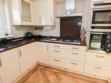 A kitchen with cream cabinets a gas stove a double oven wooden utensils and a dish rack at The Croft in Longhoughton near Alnwick