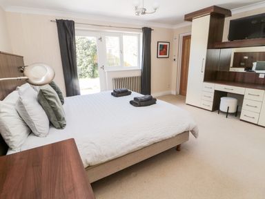 A bedroom with a bed with pillows and folded towels beside a window with curtains and a dressing table at The Croft in Longhoughton near Alnwick