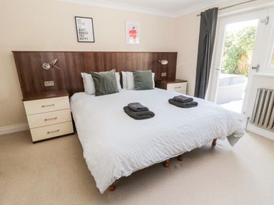 A bedroom with a large bed nightstands on each side and a door leading outside at The Croft in Longhoughton near Alnwick