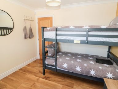 A bedroom with a bunk bed and a round wall mirror at The Croft in Longhoughton near Alnwick