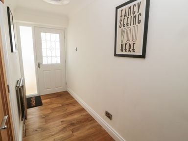 A hallway with a wooden floor a white entrance door a radiator and a framed print on the wall at The Croft in Longhoughton near Alnwick