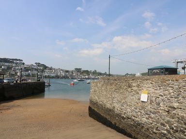 A harbor with boats on water and stone walls around a sandy beach at The Watch Below in Polruan