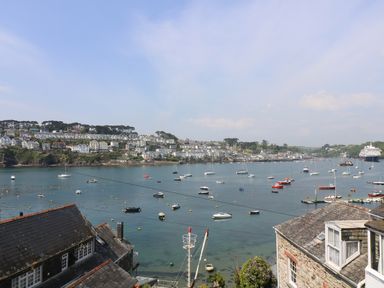 A coastal town with boats in the water and houses on the hillside at The Watch Below in Polruan