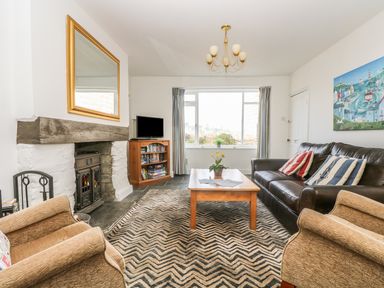 A living room with a fireplace a wooden coffee table and a leather sofa at The Watch Below in Polruan