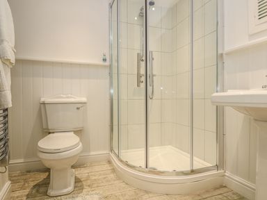 A bathroom with a toilet a corner shower enclosure and a sink at The Watch Below in Polruan