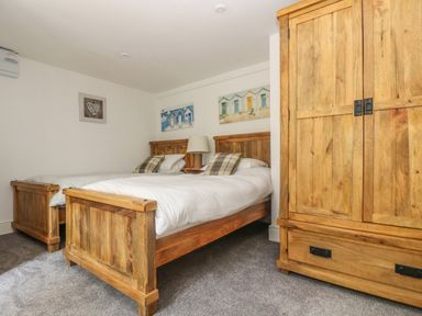 A bedroom with two single wooden beds a wooden wardrobe and a table lamp at The Watch Below in Polruan