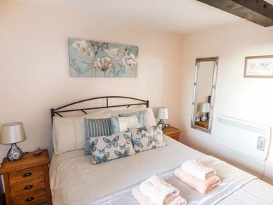 A bedroom with a bed with pillows and folded towels and bedside tables with lamps at Bank End Barn in Grizebeck
