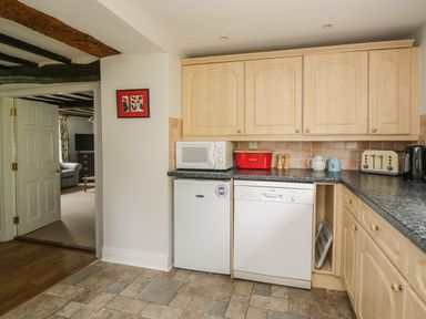A kitchen with wooden cabinets a microwave a red bread bin a dishwasher a fridge a toaster and a kettle at Hall Bank Cottage in Rydal near Ambleside
