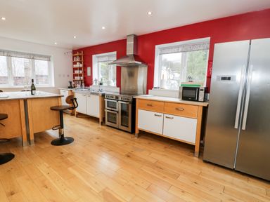 A kitchen with wooden floors appliances and red walls at Ty Coch in Llanberis
