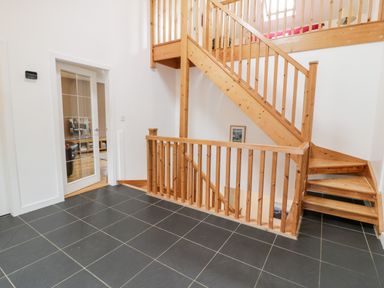 An indoor space with black tiled floor wooden staircase and white walls at Ty Coch in Llanberis