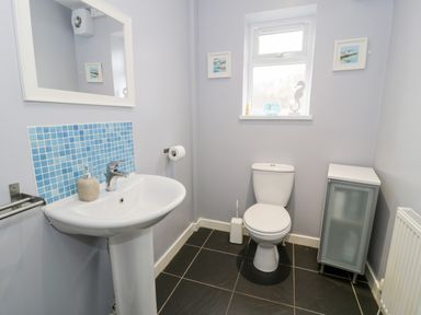 A bathroom with a pedestal sink a toilet a small cabinet and a window at Ty Coch in Llanberis