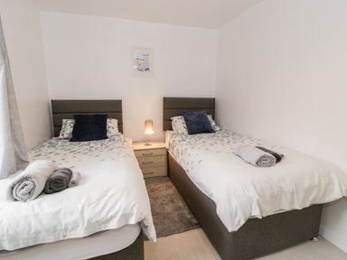 A bedroom with two single beds bedside table and lamp at Ty Coch in Llanberis