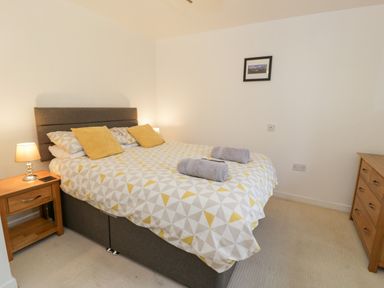 A bedroom with a double bed bedside tables lamps and a chest of drawers at Ty Coch in Llanberis