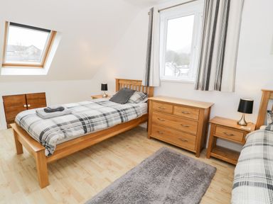 A bedroom with two single beds wooden furniture and a window at Ty Coch in Llanberis