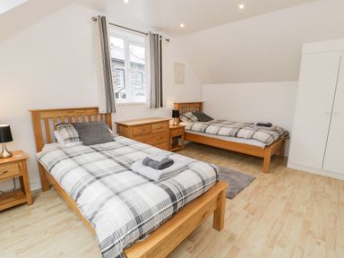 A bedroom with two single beds wooden furniture and a window at Ty Coch in Llanberis