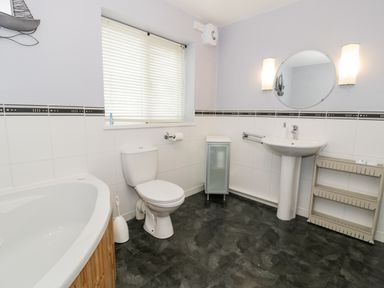 A bathroom with a bathtub toilet sink and a storage cabinet at Ty Coch in Llanberis