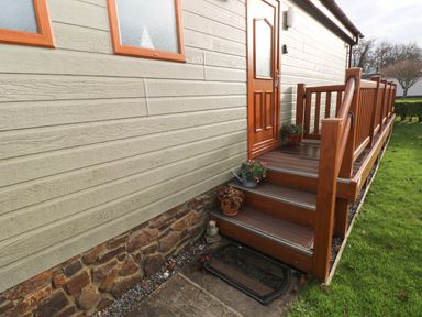 An entrance door with wooden steps and railings with potted plants on the porch at The Retreat in Wisemans Bridge near Saundersfoot