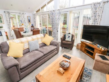 A living room with a sofa an armchair a coffee table and a television at The Retreat Wisemans Bridge near Saundersfoot
