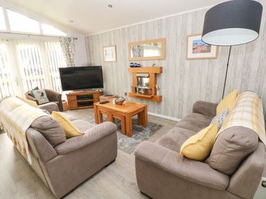 A living room with two gray sofas yellow pillows wooden coffee table and TV at The Retreat in Wisemans Bridge near Saundersfoot