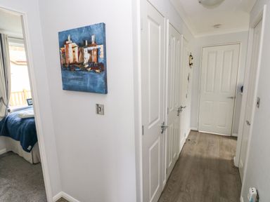 A hallway with white doors and wood flooring with a painting on the wall at The Retreat in Wisemans Bridge near Saundersfoot