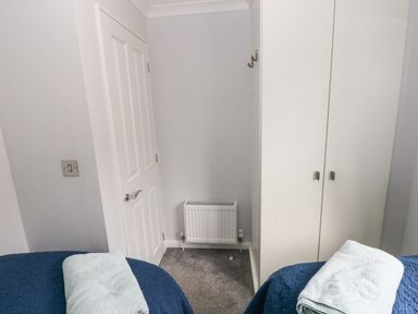 A corner of a bedroom with a white door radiator wardrobe and beds with towels at The Retreat in Wisemans Bridge near Saundersfoot