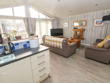 A living room with sofas a coffee table and a television next to a kitchen counter at The Retreat in Wisemans Bridge near Saundersfoot