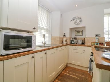 A kitchen with a microwave oven kettle toaster and a sink at Curlews Cottage in Looe