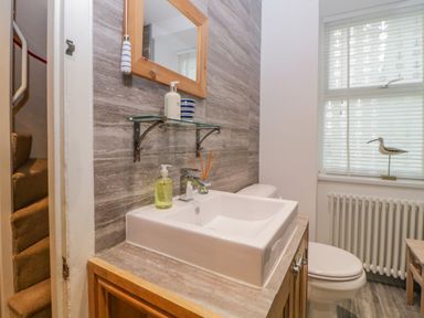 A bathroom with a sink countertop mirror window radiator and toilet at Curlews Cottage in Looe