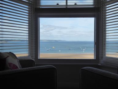 A window view of a beach and sea with boats visible from a room at 1 Beachtop Court in Tenby