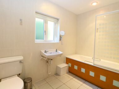A bathroom with a toilet sink and bathtub with a glass shower screen at Rookyard Cottage in Holton near Halesworth