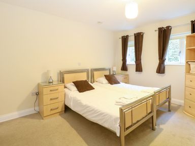 A bedroom with two single beds side by side with brown pillows and bedside tables with lamps at Rookyard Cottage in Holton near Halesworth