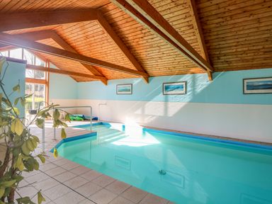 An indoor swimming pool with a wooden ceiling and framed pictures on the wall at Rookyard Cottage in Holton near Halesworth