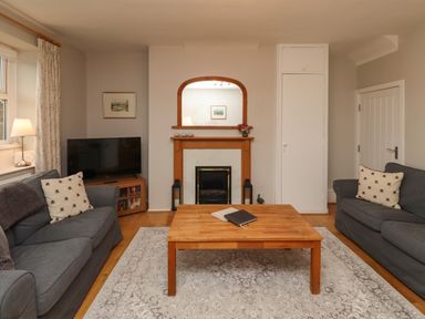 A living room with two grey sofas a wooden coffee table a fireplace and a television at Jasmine Cottage in Lesbury near Alnmouth