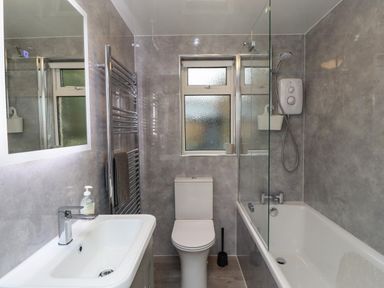 A bathroom with a sink a toilet a bathtub with shower and a window at Jasmine Cottage in Lesbury near Alnmouth