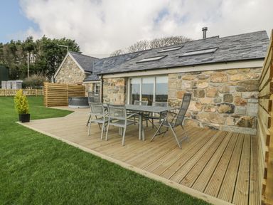An outdoor patio with a table and six chairs beside a stone house with skylights at Horseshoe Cottage in Abersoch