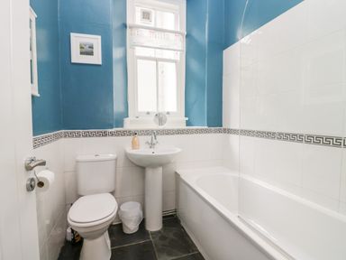 A bathroom with a toilet, pedestal sink, bathtub, and window at Ramblers Roost in Grasmere