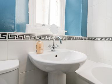 A bathroom sink with a faucet soap dispenser and a window above at Ramblers Roost in Grasmere