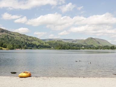 A lake with a yellow kayak on the shore and hills in the background at Ramblers Roost in Grasmere