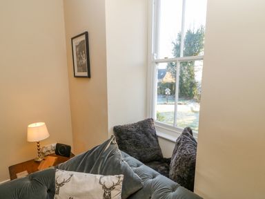 A seating area with cushions next to a window and a small table with a lamp at East Farmhouse Cottage in Humshaugh near Hexham